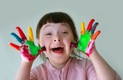 Image of a smiling young girl with paint on her hands.