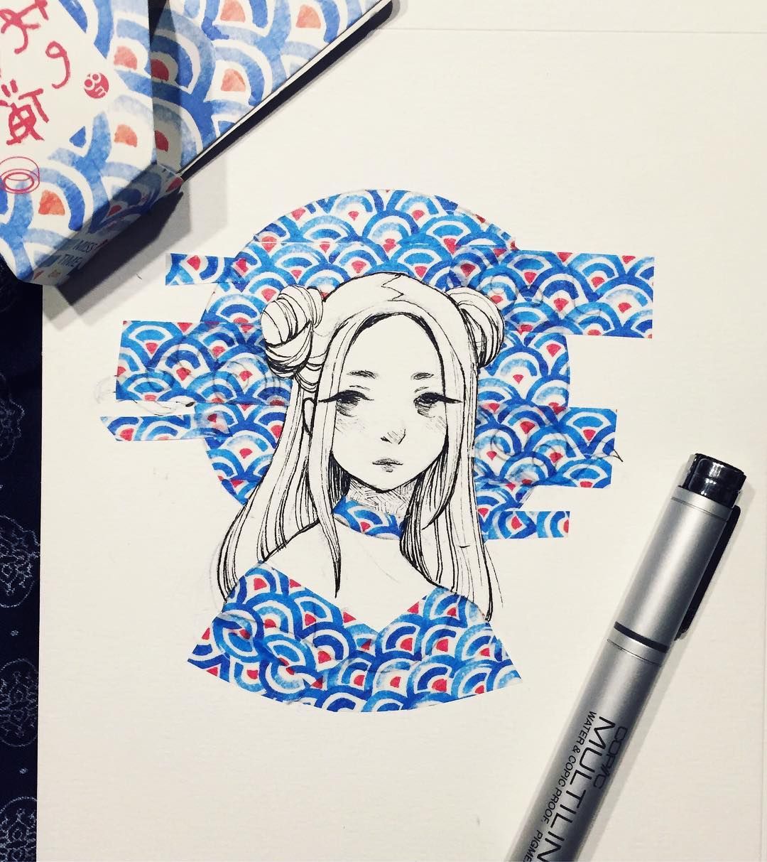 A photograph of a washi tape painting with a manga-style character with hair buns and blue circular washi tape creating their outfit and sun in the background.