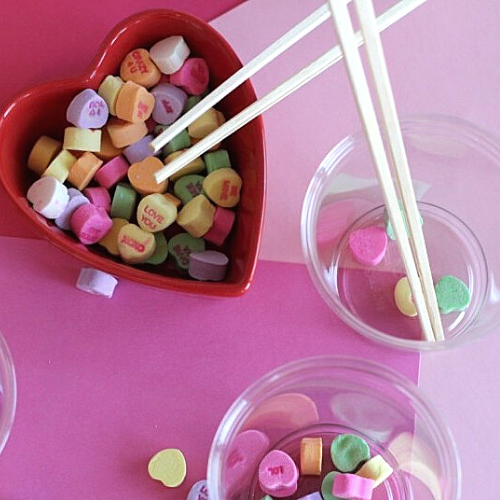 A picture of chopsticks in bowls containing Valentine's Day hearts.