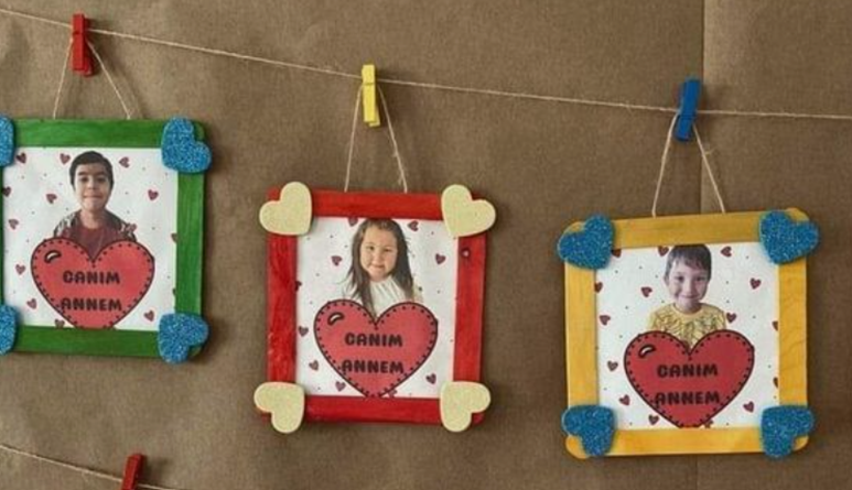 Three different colored square frames made out of popsicle sticks around a picture of a child with a heart shape.