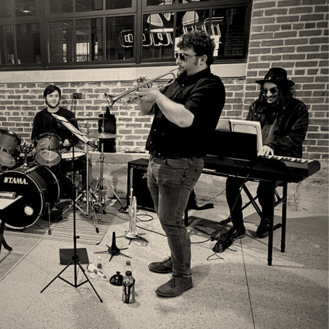 Black and white photo of three of the 4 quartet members. Keyboardist Danny Zanger on the right, trumpeter Jake Sinatra in the center, and drummer Nathan Seutter on the left.