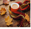 fall leaves and a knit scarf around a mug of cider