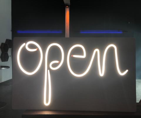 Photograph featuring a neon sign that says, "open" in a dark room.