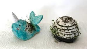 A clay narwhal and a clay snail with small chia plants growing out of them.