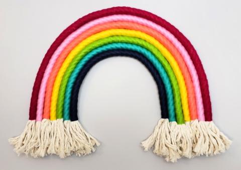 A photograph of a rainbow made out of different colors of rope with fringed ends. 