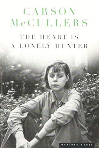 The Heart is a Lonely Hunter book cover. Black and white photo of the young author Carson McCullers sitting with her arms over her legs looking into the camera.