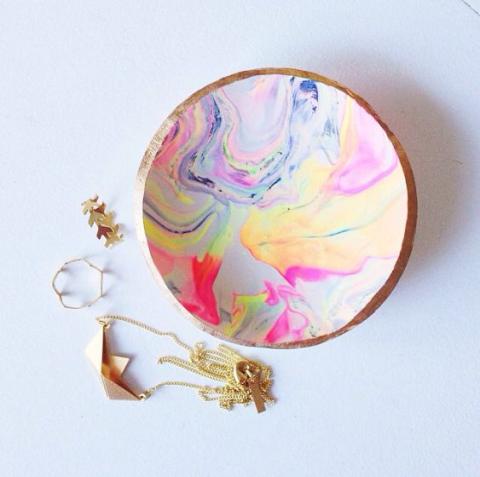 A photograph featuring a small marbled dish with gold jewelry next to it.