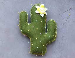 A picture of a cactus made from green felt with sewing pins on it.