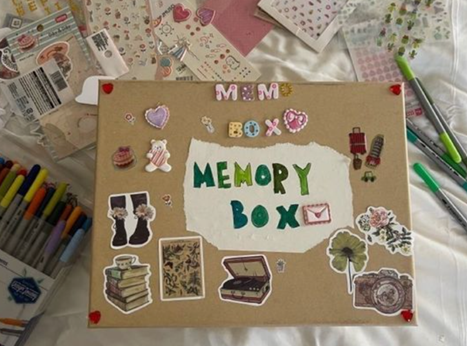 A cardboard box covered with stickers and letters that spell, 'Memory Box'.