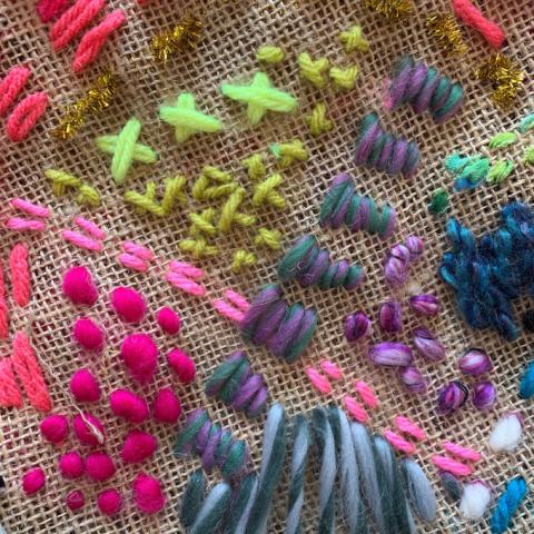 A closeup of burlap with colorful, simple stitches. Photo credit: Artbarblog.com