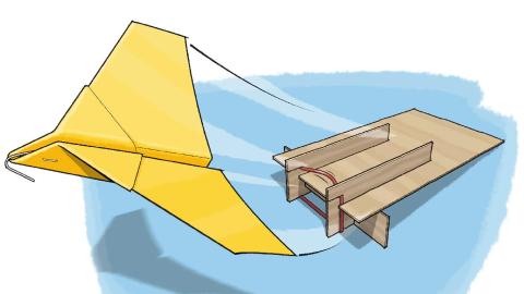 A paper plane being launched from a cardboard ramp with a rubber band. 