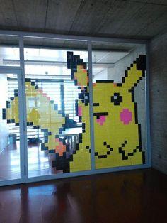 A picture featuring the Pokémon Pikachu, made out of sticky notes on large glass windows. 