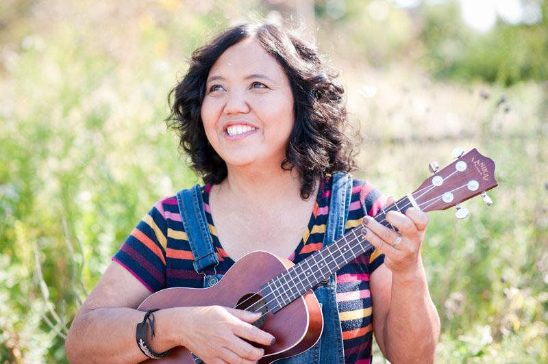 Image of Miss Ann holding a ukulele and smiling into the distance