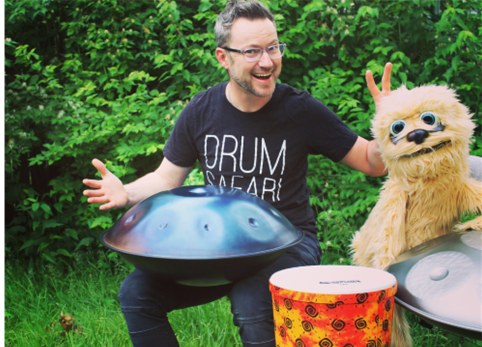 A photo of a man with glasses and 3 drums.