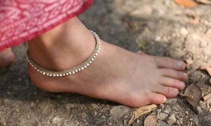 Photo of a bare foot wearing a macramé and beaded anklet.