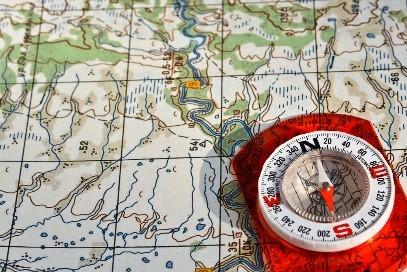 A red compass pointing north on top of a map.