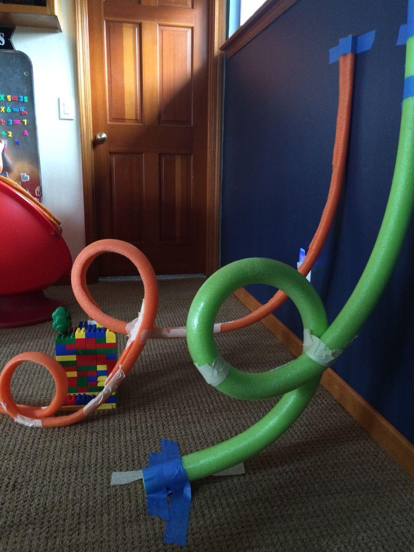 A picture of pool noodles repurposed as roller coasters help together with duct tape and LEGOs.