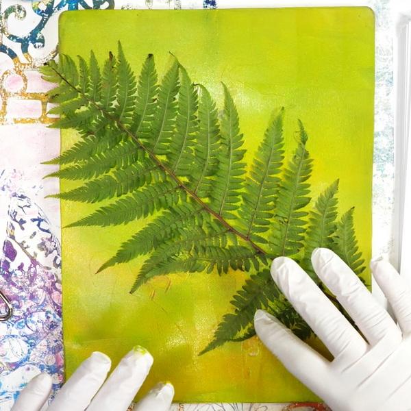 Photo of someone pressing leaves into a colorful, paint-covered surface. Photo credit: Hopalongstudio.com