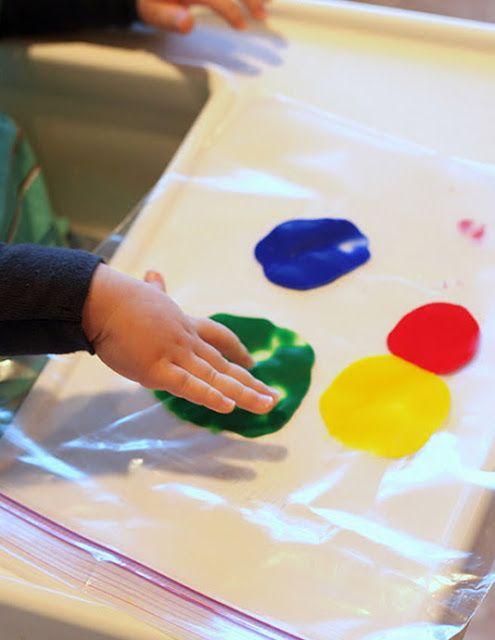 Photo of a toddler pressing on paint through a plastic bag.