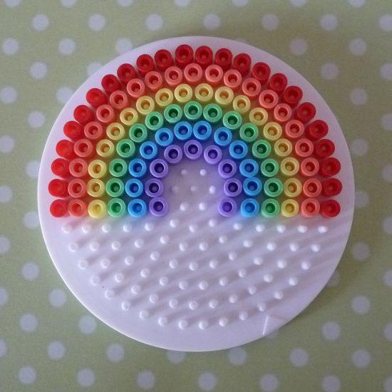 A photo of perler beads on a peg board forming a rainbow.
